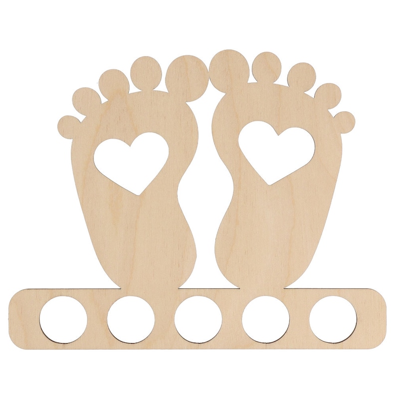 May include: A light-colored wooden baby feet-shaped decoration with a heart cut out of each foot. The decoration has a row of five circular holes at the bottom, likely for holding items. The design is simple and suitable for a nursery or baby-themed decor.