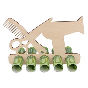 May include: A wooden money holder shaped like a comb, scissors, and a hairdryer. The holder has five slots, each containing rolled-up Euro banknotes. The design is light brown, with the banknotes adding green and yellow accents.