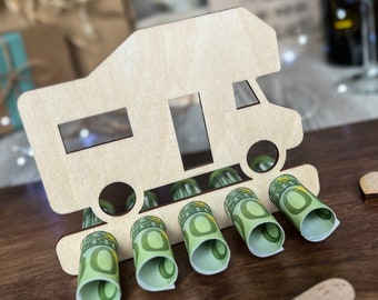 Könnte beinhalten: Holz-Wohnmobil-Geldhalter mit Schlitzen für gerollte Geldscheine. Das Wohnmobil ist in einer hellen Holzfarbe lackiert und hat einen weißen Hintergrund.