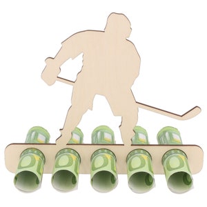 May include: Wooden hockey player money holder with five slots for euro bills. The player is holding a hockey stick and is standing on a wooden base.