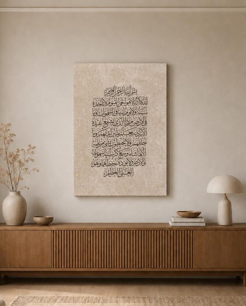 May include: A rectangular wall art piece featuring intricate black Arabic calligraphy printed on a textured, light beige canvas. The script is arranged in a vertical block format, centered on the canvas, showcasing traditional lettering styles.