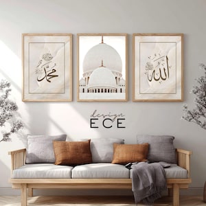 May include: Three framed art prints with a beige marble effect background. The prints feature Arabic calligraphy and a white mosque with a dome. The frames are light brown. The text "design ECE" is below the prints.