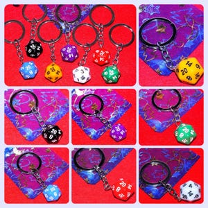 May include: A set of nine keychains featuring 20-sided dice in various colours, including black, red, green, purple, yellow, and blue. Each die has white numbers.
