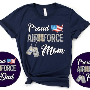 May include: Navy blue t-shirt with the words "Proud Air Force Mom" in white script, along with an American flag graphic. Includes two circular designs with "Proud Air Force Dad" and "Proud Air Force Papa" text.