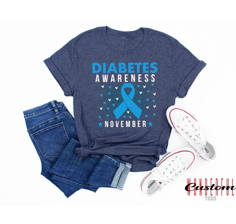 K&ouml;nnte beinhalten: Ein blaues T-Shirt mit dem Text "Diabetes Awareness November" und einem blauen Band. Das Shirt hat eine melierte blaue Farbe und ist aus einem weichen, bequemen Material gefertigt.
