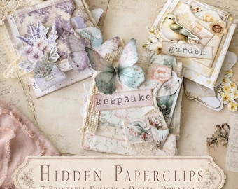 Op de afbeelding: Een verzameling decoratieve paperclips met gelaagde papierontwerpen met bloemen-, vlinder- en vogelmotieven. De items bevatten labels met de tekst "e notes", "garden" en "keepsake", geaccentueerd met kant en vintage papiertexturen.