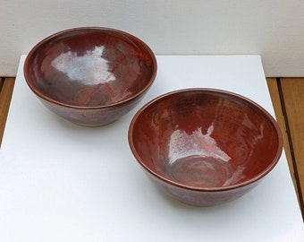 Two hand thrown stoneware orange red bowls with a turned foot. Approximately 15 cms diameter 6 cms high, breakfast / soup bowls.