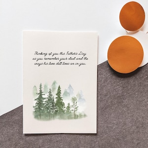 May include: A Father's Day card with a watercolor forest scene. The card has a message in script that reads, "Thinking of you this Father's Day as you remember your dad and the ways his love still lives on in you."