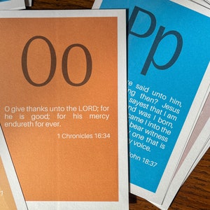 May include: Two orange cards with the letter "O" printed in black on each card. The cards are stacked on top of each other. The top card has the text "O give thanks unto the LORD; for he is good; for his mercy endureth for ever. 1 Chronicles 16:34" printed in black on the bottom half of the card.