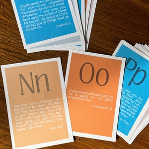 May include: Four colourful cards with large letters and scripture verses. The cards are orange, blue, and pink. The letters are N, O, P, and A. The verses are from the Book of Mormon, the Bible, and the Book of Alma.
