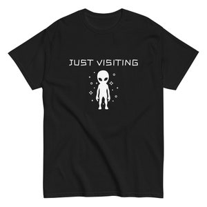 May include: Black t-shirt with a white alien graphic and the text "JUST VISITING" printed on the front.