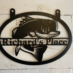 May include: Black metal oval sign with a cutout of a bass fish and the text "Richard's Place" in a banner below the fish.