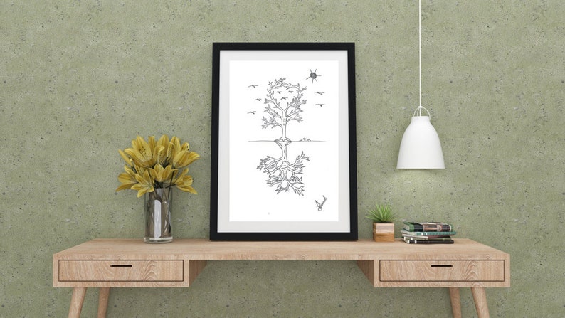 May include: Black and white line art print of a tree with roots and birds flying above. The print is framed in a black frame and hanging on a green wall above a wooden desk.