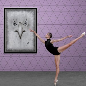 K&ouml;nnte beinhalten: Eine Ballerina in einem schwarzen Trikot und Spitzenschuhen vollf&uuml;hrt eine anmutige Pose vor einem gerahmten Bild eines Adlerkopfes. Der Hintergrund ist eine violette Wand mit einem geometrischen Muster.