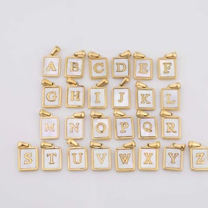 May include: Gold-toned alphabet pendants, each featuring a white mother-of-pearl inlay and a capital letter. The pendants are rectangular with rounded corners and a small loop at the top for a chain. The letters A through Z are displayed.