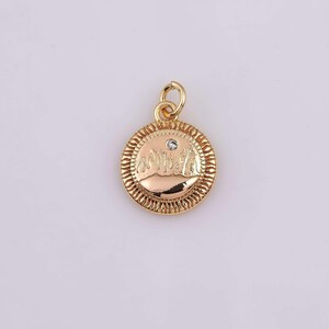 May include: A gold-colored pendant with a circular design. The pendant features a textured border and a central design with a small, clear gemstone. The pendant has a loop for attaching to a chain.