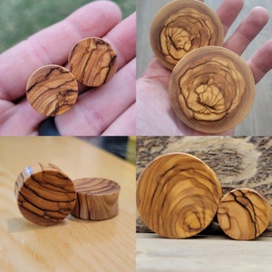 May include: A set of four wooden ear gauges, each with a unique wood grain pattern. The gauges are made of olive wood and have a natural finish.