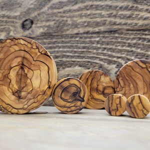 May include: A set of six olive wood ear gauges in various sizes. The gauges are round and have a natural wood grain pattern.