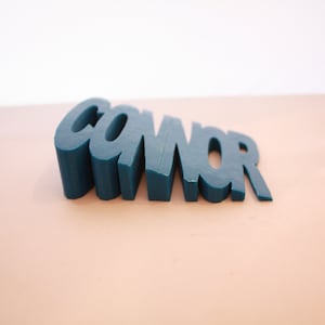 May include: A teal blue doorstop shaped like the word "CONNOR".