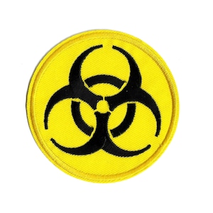 May include: Round yellow patch with a black biohazard symbol. The patch has a stitched border and is set against a white background. The biohazard symbol is a warning sign for biological hazards.