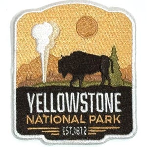 May include: Embroidered patch featuring a Yellowstone National Park design. The patch depicts a bison, geyser, and pine tree against a golden sunset backdrop. Text includes "YELLOWSTONE NATIONAL PARK" and "EST. 1872".