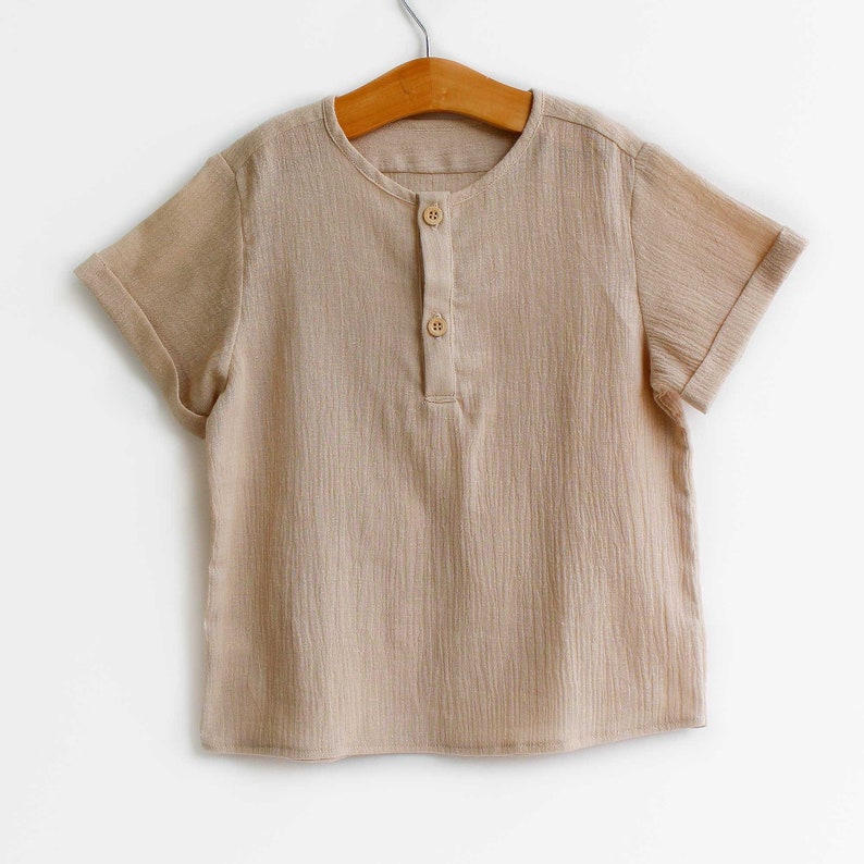 Pu&ograve; includere: Una camicia beige a maniche corte con scollo a bottoni. La camicia &egrave; realizzata in un tessuto morbido e testurizzato.