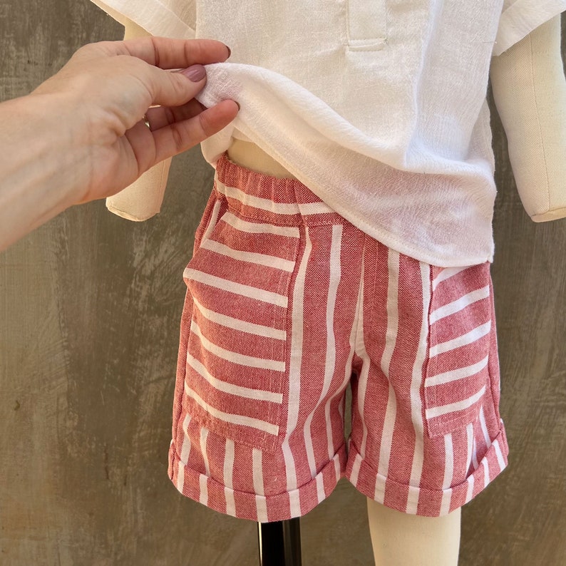 May include: Red and white striped shorts with cuffed hems. The shorts have two pockets on the front.