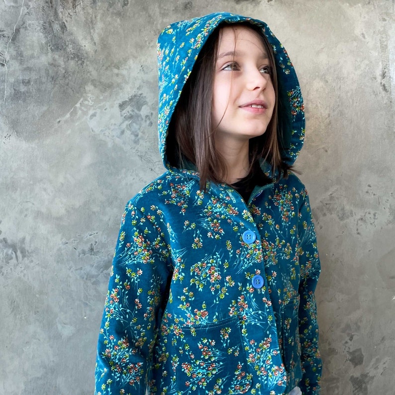 May include: A teal blue hooded jacket with a floral pattern. The jacket has a button closure and a patch pocket on the front.