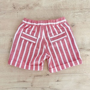May include: Red and white striped shorts with two back pockets. The shorts have a white elastic waistband.