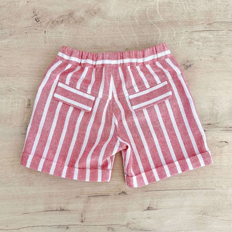 May include: Red and white striped shorts with two back pockets. The shorts have a white elastic waistband.