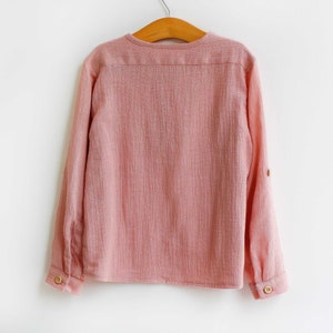 Pu&ograve; includere: Una camicia rosa a maniche lunghe con bottoni e vestibilit&agrave; rilassata. La camicia ha un colletto e una chiusura con bottoni sul davanti.