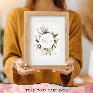 May include: A framed print with the text "Happy Mother's Day" surrounded by green leaves and pink accents. The frame is light brown and holds a 5"x7" print. The image also includes the text "TURN YOUR CARD INTO ART YOU CAN DISPLAY".
