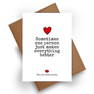 Puede incluir: Una tarjeta de felicitación blanca con sobre marrón que presenta un icono de corazón rojo y el texto negro estilo máquina de escribir: Sometimes one person just makes everything better. Debajo, dos corazones rojos y: You are that person.