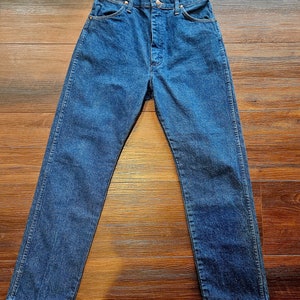 May include: A pair of dark blue denim jeans with a button fly and five pockets.
