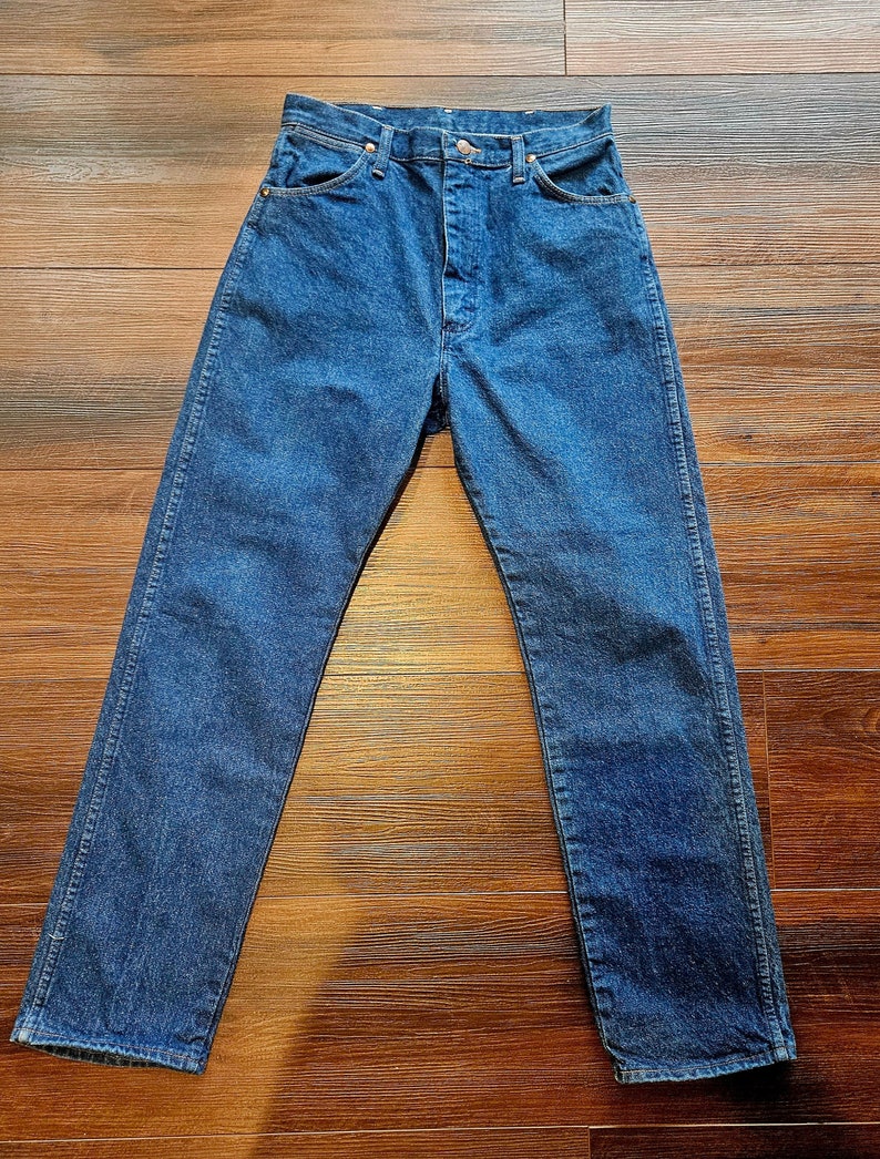 May include: A pair of dark blue denim jeans with a button fly and five pockets.