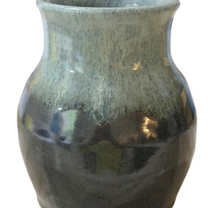 May include: A handcrafted ceramic vase with a two-tone glaze. The upper portion is a muted teal, transitioning to a deep charcoal at the base. The vase has a rounded body and a slightly flared rim, suitable for floral arrangements.