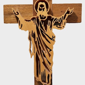 May include: Wooden cross with a carved figure of Jesus Christ. The figure is light brown, with outstretched arms, and is set against a darker brown cross. The letters "INRI" are at the top of the cross.