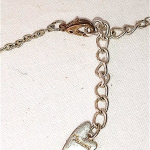 Op de afbeelding: Zilveren ketting met een hartvormige hanger met de tekst "Juicy Couture".