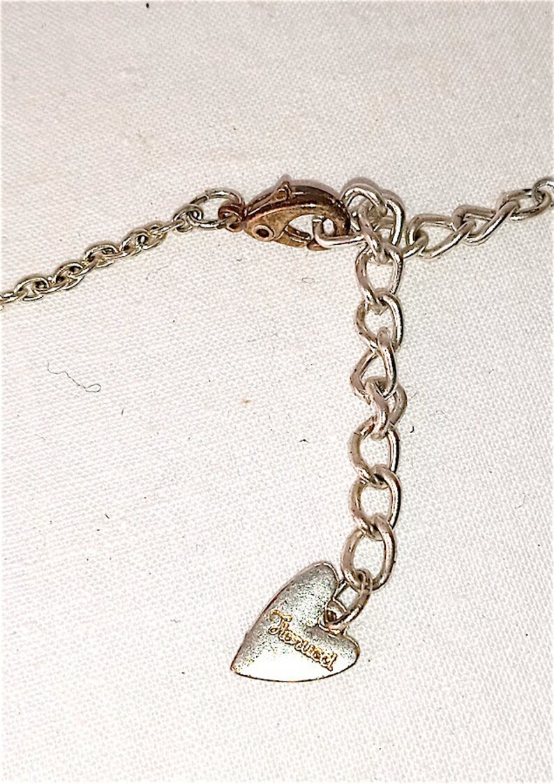 Op de afbeelding: Zilveren ketting met een hartvormige hanger met de tekst "Juicy Couture".