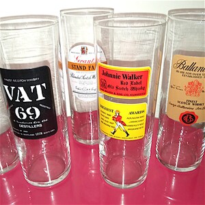 May include: Five clear glass tumblers with different Scotch whisky labels. The labels feature the brands Vat 69, Grant's Stand Fast, Johnnie Walker Red Label, and Ballantine's Finest Scotch Whisky.