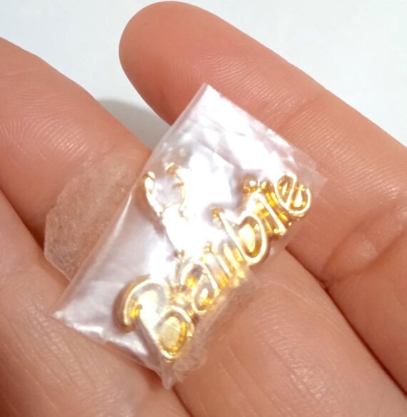 B864 - BARBIE TROPICAL SPLASH 1993 ciondolo dorato plastica con scritta Barbie gadget nuovo ancora sigillato