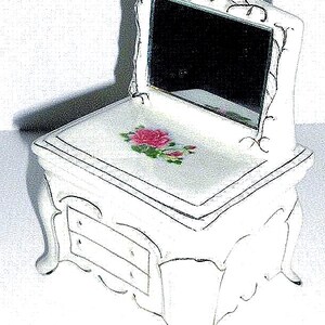 Può includere: Un set da toeletta in porcellana bianca con uno specchio a forma di cuore e un cassetto. Il set da toeletta ha un design floreale con una rosa rosa.