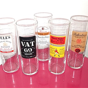 May include: Five clear glass tumblers with labels for different brands of Scotch whisky. The labels include Bell's, Vat 69, Grant's Stand Fast, Johnnie Walker Red Label, and Ballantines.
