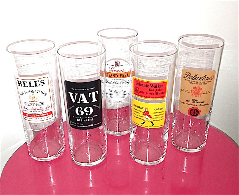 May include: Five clear glass tumblers with labels for different brands of Scotch whisky. The labels include Bell's, Vat 69, Grant's Stand Fast, Johnnie Walker Red Label, and Ballantines.