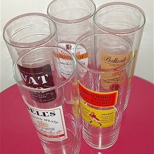 May include: Five clear glass tumblers with different Scotch whisky labels. The labels include "VAT 69", "Bell's", "Grants", "Ballantine's", and "Johnnie Walker Red Label".
