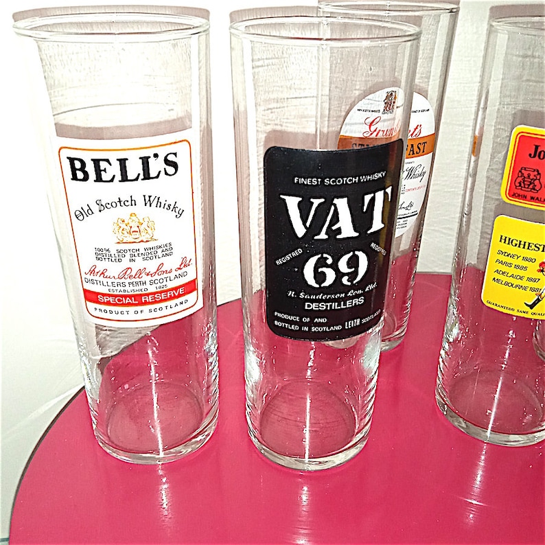 May include: Four clear glass tumblers with labels for different brands of Scotch whisky. The labels include Bell's Old Scotch Whisky, Vat 69, Grant's, and John Walker & Sons.