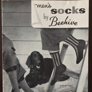 May include: Vintage advertisement for men's socks by Beehive. The image shows two pairs of patterned socks, one with a herringbone design and the other with vertical stripes. A black dog is in the background. The price is 35 cents.