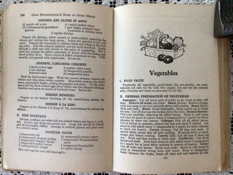 May include: A vintage cookbook open to a page titled "Vegetables" with a black and white illustration of a basket of vegetables. The text on the page discusses the nutritional value of vegetables and provides instructions for preparing them.