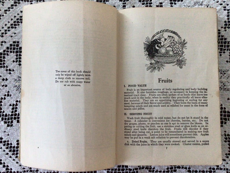 May include: A vintage book cover with a black and white illustration of a basket of fruit. The book title is "Fruits" and the text discusses the food value and serving of fruits.