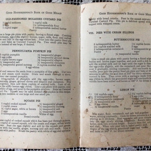 May include: A vintage cookbook with recipes for old-fashioned molasses custard pie, Pennsylvania pumpkin pie, squash pie, butterscotch pie, and lemon pie. The book is open to a page with instructions for making the pies.